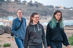 Three young people walking outdoors with blurred hillside landscape background