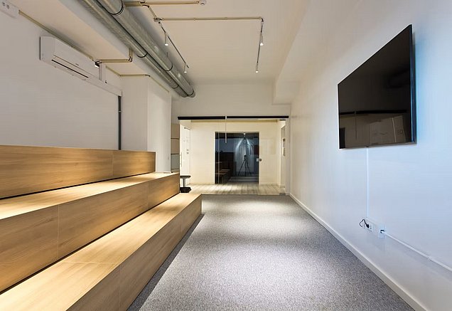 Modern auditorium at Edifício Transparente in Porto, with tiered wooden seating, a presentation screen, and a wall-mounted display.